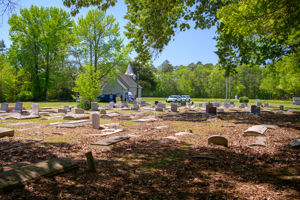 Photo of cemetery with gravestones and Malone's Church in the background.