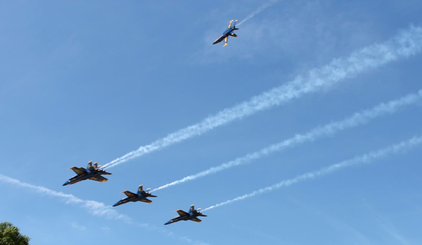 Four Blue Angels jets flying in the sky.