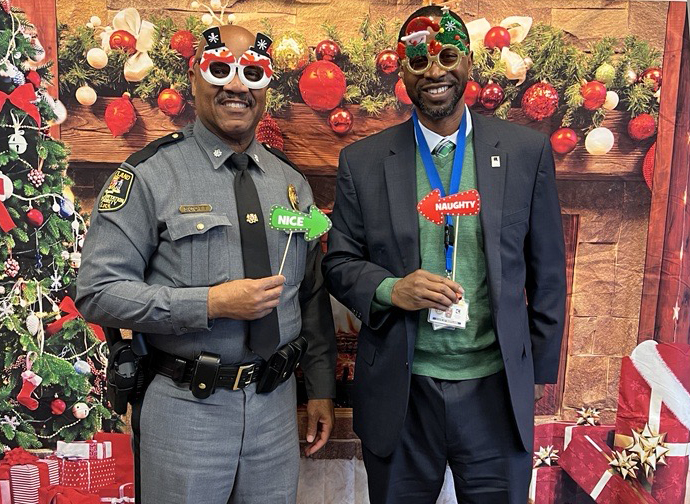 A festive red and green holiday photo with Former MDTA Police Chief Col. Josephy F. Scott and Assistant Secretary Percy Dangerfield.