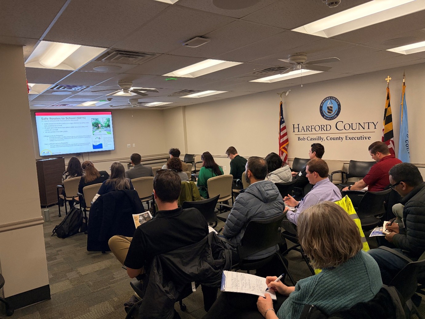 People sitting in chairs taking notes during an MDOT Grants Roadshow presentation.